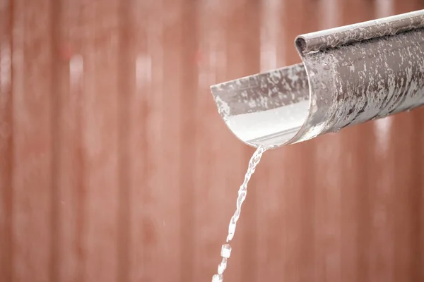 water flows through the drain pipe. snow is melting.