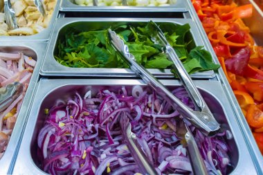 salata barı. yemek odasında doğranmış mor soğan. yeşil salata, kırmızı biber, pastırma. 