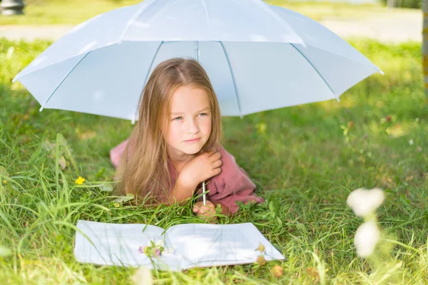 Niño está descansando sobre la hierba verde en verano. niña leyendo un libro — Foto de Stock