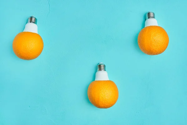 three oranges in a light bulb on a turquoise background