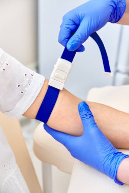 Kız kan verir. Doktor koluna tıbbi turnike uyguladı.