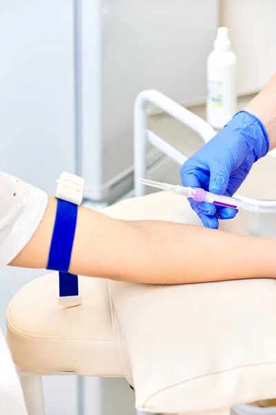 Kadın kan verir. Doktor elinde bir şırınga tutuyor.
