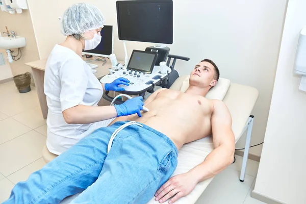 Bir erkekte karın ultrasonu. Doktor ultrason cihazları üzerinde çalışıyor.