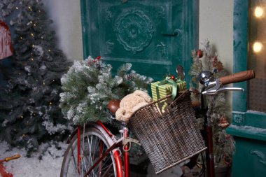Noel ve yeni yıl kutlaması. Evin yakınındaki karla kaplı bir sokakta bir Noel ağacı ve içinde hediye sepeti olan kırmızı bir bisiklet var.