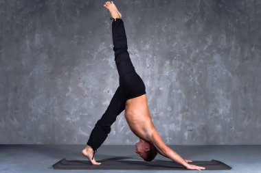 Genç adam bir yoga poz eka pada adho mukha svanasana gerçekleştirme