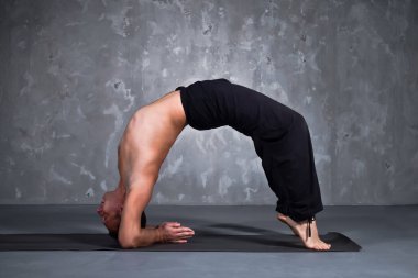 Genç adam bir yoga poz Chakrasana gerçekleştirme