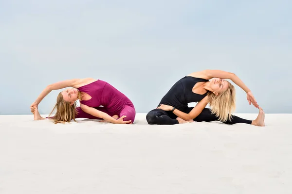 Due Belle Giovani Donne Praticano Yoga Sulla Sabbia Parivritta Janu — Foto Stock