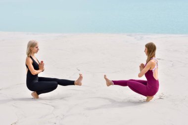 Sahilde yoga yapan iki güzel genç kadın.