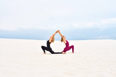 Kumda birlikte yoga yapan iki güzel genç kadın.