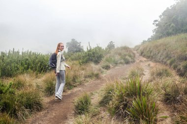 Güzel neşeli kız Horton Plains Milli parkta yürüyor. Sri Lanka. Bulutlar, sis ve dağlar