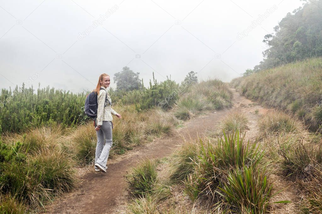 Beautiful cheerful Girl walks in the Horton Plains National Park. Sri Lanka. Clouds, Fog and Mountains