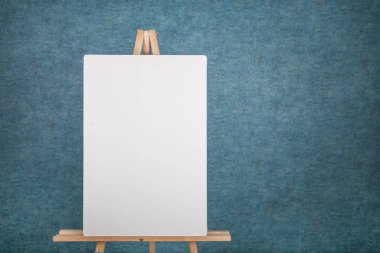 Mavi bir duvara boş tuval ile ahşap şövale