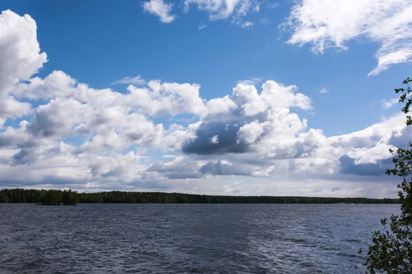 Göl güzellik. Mavi gökyüzünün suya yansıtılır. Rüzgar küçük bir dalgalanma gölün yüzeyi boyunca döner. Yeşil ağaçlar su için inerler. Plaj taş Dağları'nın kalıntıları oluşur. Konchozero. Karelya. Rusya.