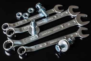 Metal vidalar, pullar, fındık ve anahtarları bir siyah arka plan ayna. Harika kontrast görüntü