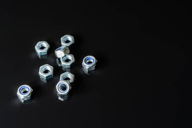 Metal vidalar, pullar, fındık ve anahtarları bir siyah arka plan ayna. Harika kontrast görüntü