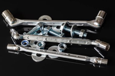 Metal vidalar, pullar, fındık ve anahtarları bir siyah arka plan ayna. Harika kontrast görüntü