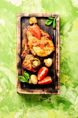 Biftek ızgara et, domates, otlar ve baharatlar kesme tahtası üzerinde. Barbekü et