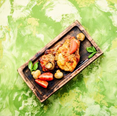 Biftek ızgara et, domates, otlar ve baharatlar kesme tahtası üzerinde. Barbekü et