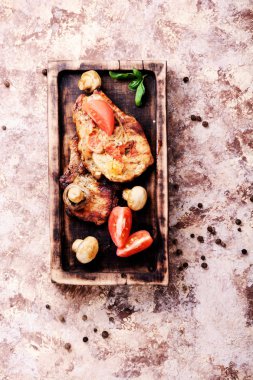 Biftek ızgara et, domates, otlar ve baharatlar kesme tahtası üzerinde