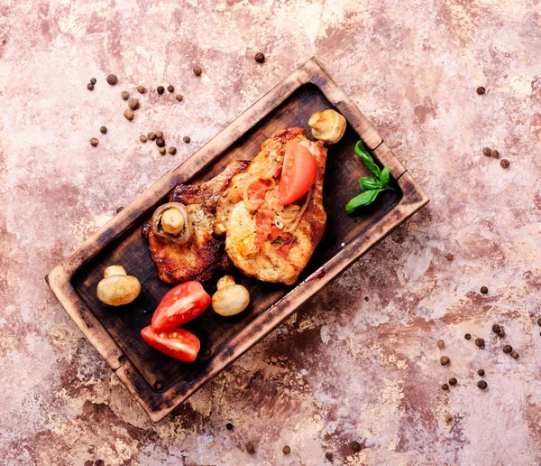 Biftek ızgara et, domates, otlar ve baharatlar kesme tahtası üzerinde. Barbekü et