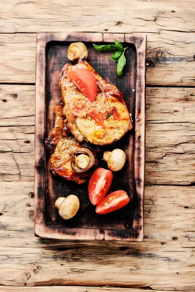 Biftek ızgara et, domates, otlar ve baharatlar kesme tahtası üzerinde