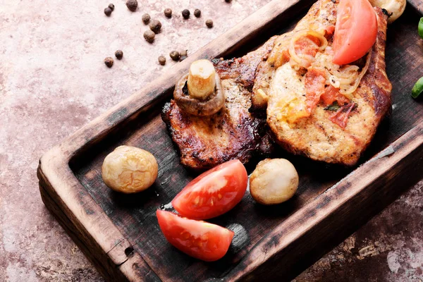 Biftek ızgara et, domates, otlar ve baharatlar kesme tahtası üzerinde. Barbekü et