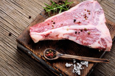 Çiğ mermer et biftek, biber eski ahşap tahta üzerinde. Dana kaburga eti