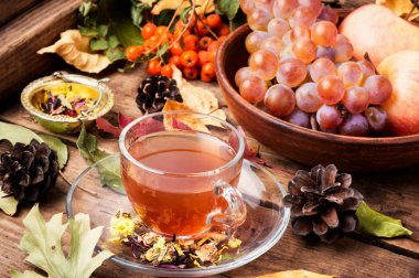 Bir fincan çay sonbahar bir arka plan üzerinde düşen yapraklar, elma ve üzüm. Sonbahar natürmort