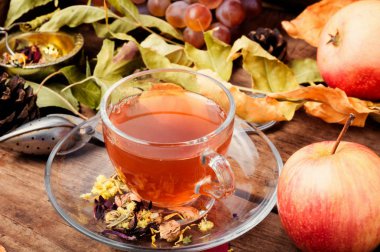 Bir fincan çay sonbahar bir arka plan üzerinde düşen yapraklar, elma ve üzüm. Sonbahar kartpostal