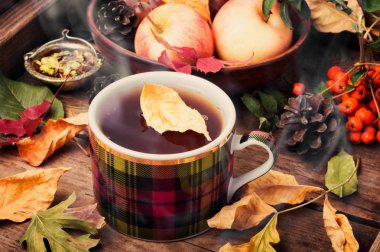 Bir fincan çay sonbahar bir arka plan üzerinde düşen yapraklar, elma ve üzüm. Sonbahar kartpostal