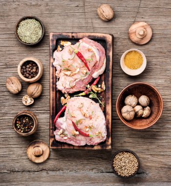 Biber, baharatlar ve ceviz ile kesme tahtası üzerinde çiğ biftek.