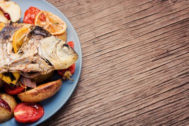 Patates ve ahşap masa üzerinde limon ile ızgara balık