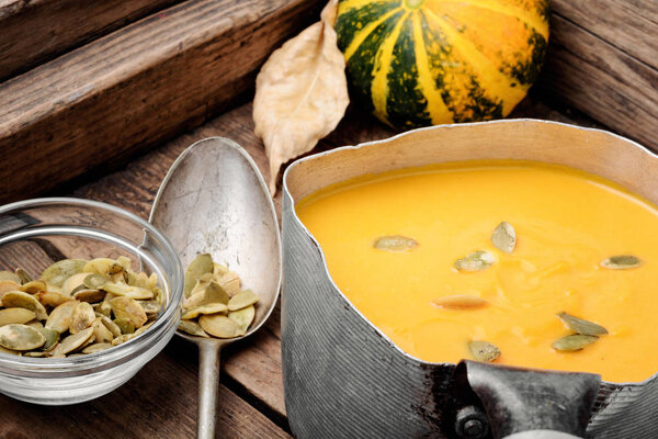 Vegetarian autumn pumpkin cream soup in a metal saucepan. Autumn food