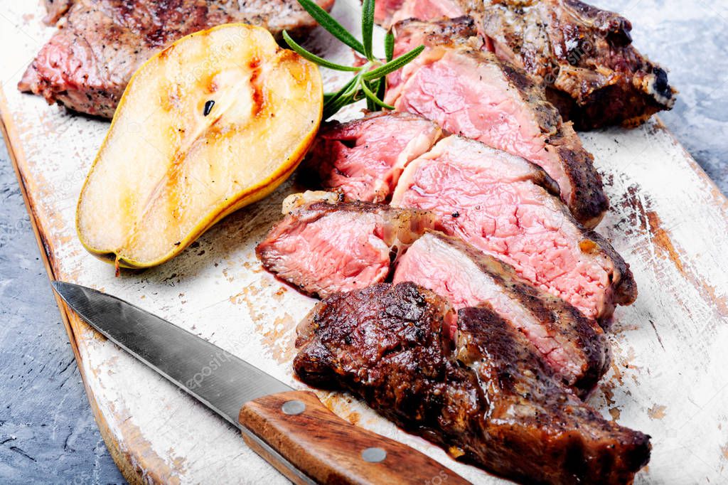 Roasted sliced grill steak with pear sauce on cutting board