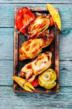 Turuncu ve elmalı bıldırcın. Kesme tahtasında kavrulmuş bıldırcın.