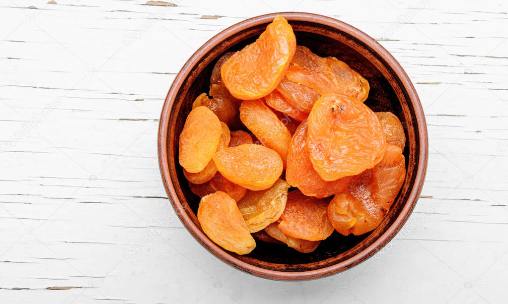 Delicious dried apricots in a bowl on white background