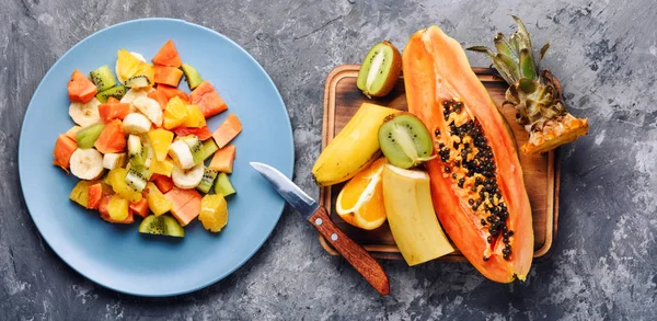 Fresh fruit salad on gray stone table.Preparing a healthy spring fruit salad