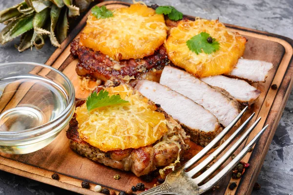 Sliced grilled roast meat with pineapple on wooden cutting board.American food