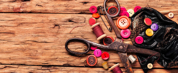 Катушки ниток и основные швейные инструменты на деревянных столах.
