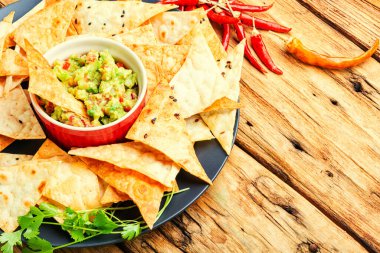 Eski ahşap bir masada mısır cipsi ve ev yapımı guacamole.