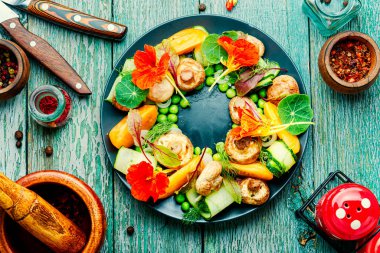 Nasturtiyum çiçekleriyle süslenmiş yaz sebze salatası.