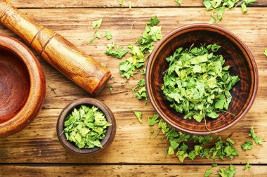 Ahşap masada kurutulmuş yeşil maydanozdan yapılmış konserve ya da baharat.