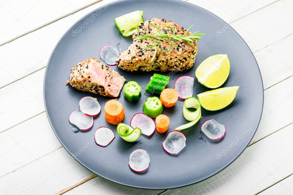 Baked tuna steak with vegetable garnish.Fish cooked with vegetables.