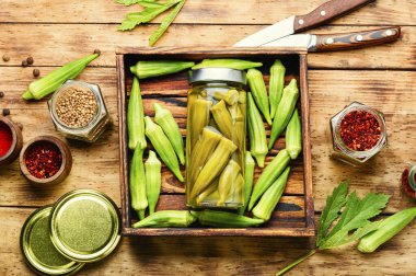 Ev yapımı sonbahar sebze koruyucusu. Tahta masa üzerinde turşulu bamya.