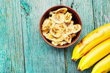 Olgun taze ve kurumuş muz. Tahta zeminde kurutulmuş tatlı. Uzayı kopyala.