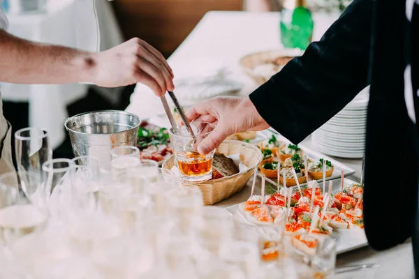 Garson misafire bardağa buz koyar.