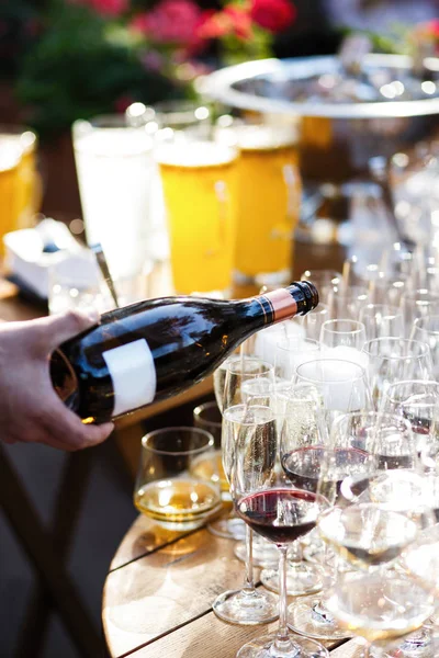 Garson şampanya dolduruyor.