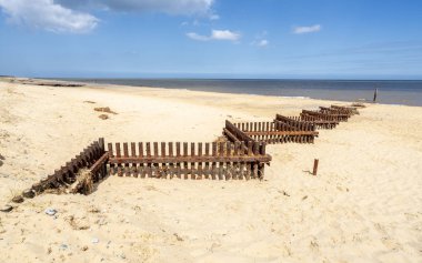 İngiltere'de bir kum Norfolk plajındaki paslı demir fırtına savunma bariyerleri