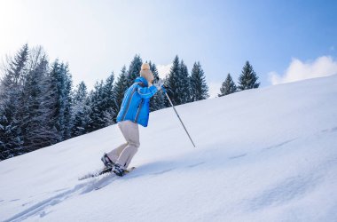 Kadın kar ayakkabıları ile orman Güney Almanya'da Oberstdorf, Bavyera Alpleri'nde kış manzara kar izinde hiking. Güzel manzara ile iğne yapraklı ağaçlar ve beyaz kar. Kış spor aktivitesi.