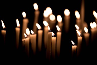 Many burning candles - Light of candles in the church on the black background clipart